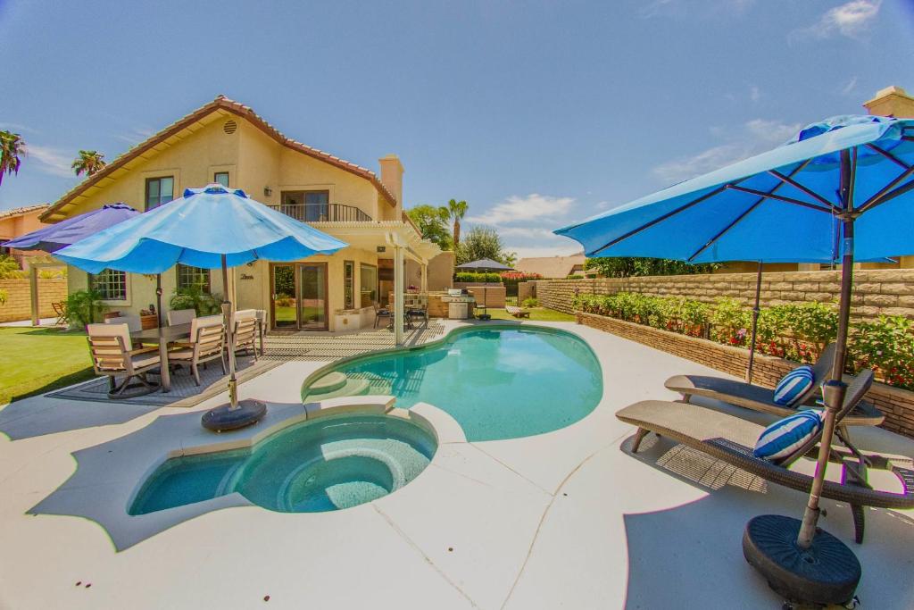 a swimming pool with chairs and umbrellas and a house at Pool & Yard Games! Group Retreat in La Quinta in La Quinta