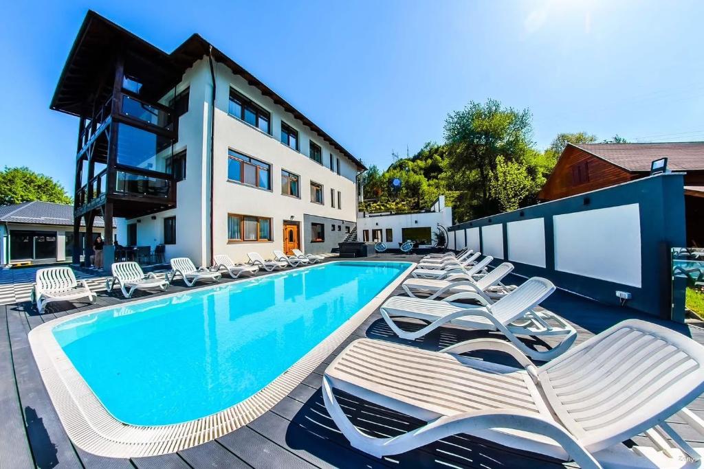 a swimming pool with lounge chairs next to a building at Panorama Lake Resort in Bezidu Nou