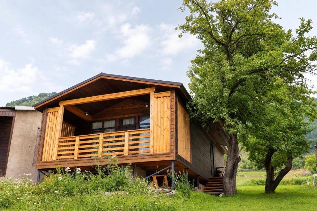 a wooden house with a tree in front of it at Cottage Deera in Mestia