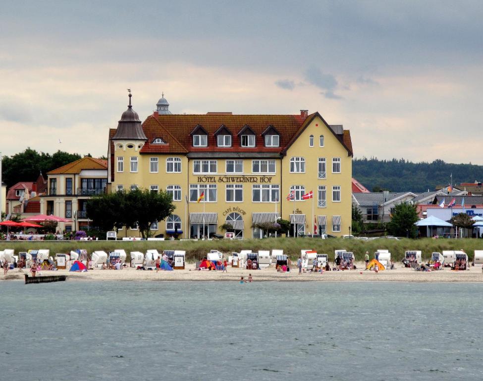 un gran edificio amarillo en una playa con gente en él en Hotel Schweriner Hof en Kühlungsborn