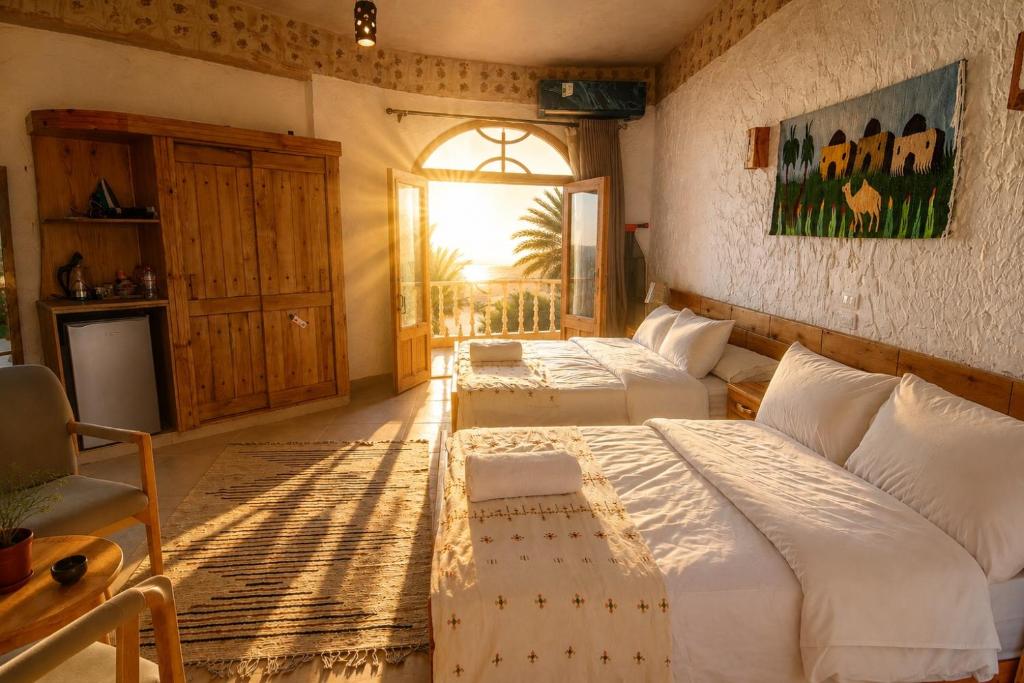 a bedroom with two beds and a chair and a window at Breezy island Hotel in Siwa