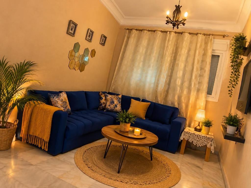 a living room with a blue couch and a table at chic appart vue sur piscine in Tangier