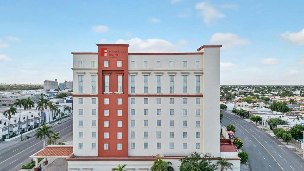 a white and red building with a street in the background at Fiesta Inn Ciudad Juarez in Ciudad Juárez