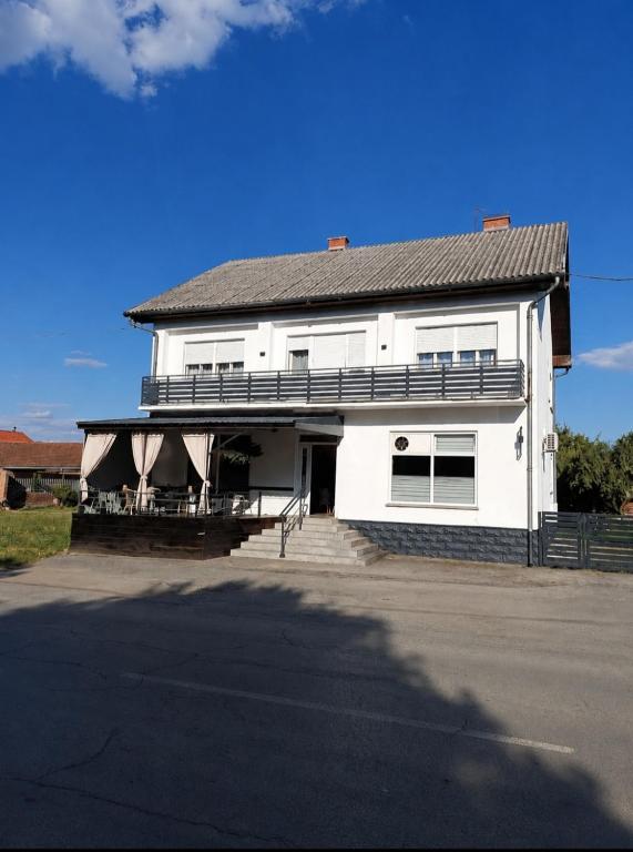 a white house with a porch and a roof at L&M Apartman in Virje