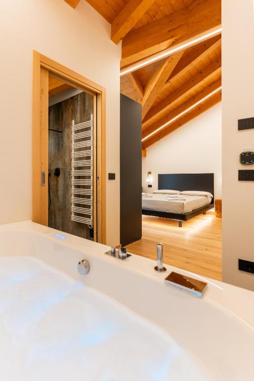 a bathroom with a tub and a bedroom in the background at Hotel Villa Amabile in Villa dʼAllegno