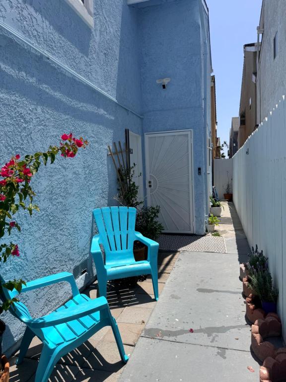 two blue chairs sitting on a sidewalk next to a building at Two Bedroom Beach Apartment in Sunset Beach