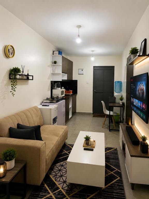 a living room with a couch and a table and a kitchen at Residence Next Door Sunset in Kiambu