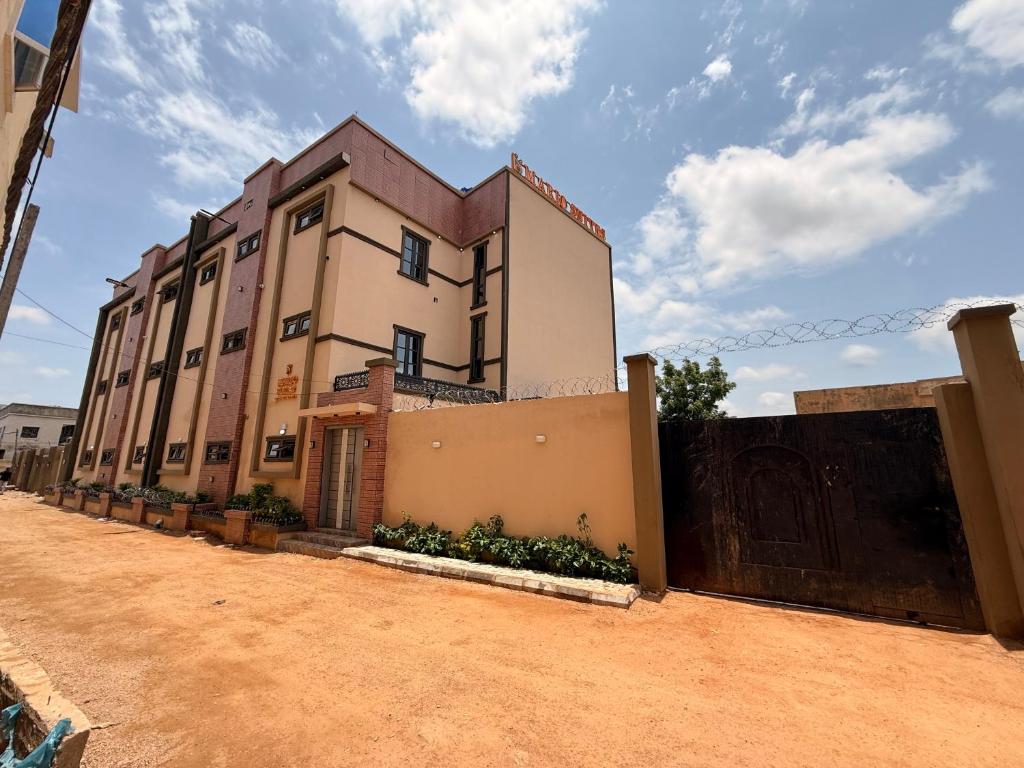 a building on a dirt road next to a fence at Mario Suites Ltd in Kano