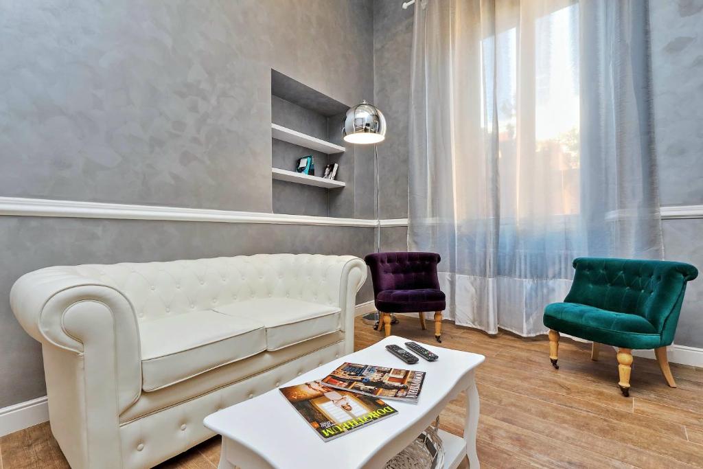 Luxury Apartment Sabina 50 mt from Trevi Fountain في روما: غرفة معيشة مع أريكة بيضاء وكرسيين