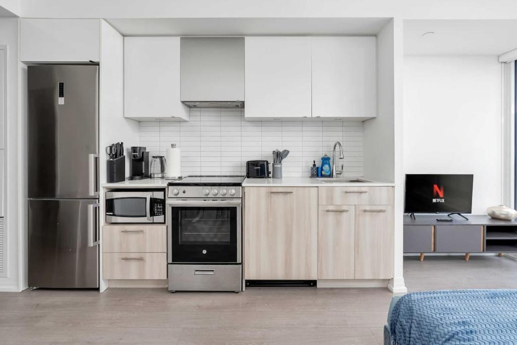 a kitchen with white cabinets and a stove and refrigerator at Executive Studio w Balcony Steps to Eaton Centre in Toronto