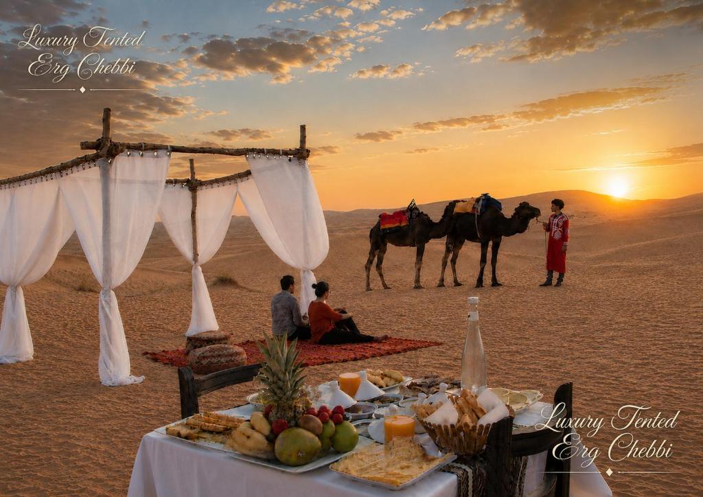 a table in the desert with a group of people and horses at Luxury Tented Erg Chebbi in Merzouga