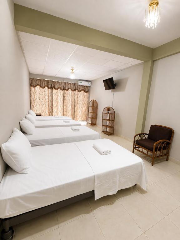 a bedroom with three beds and a chair at Residencial Turístico Rio Guayas in Guayaquil
