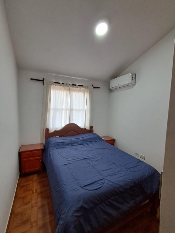 a bedroom with a blue bed and a window at Departamento Blach in Cafayate