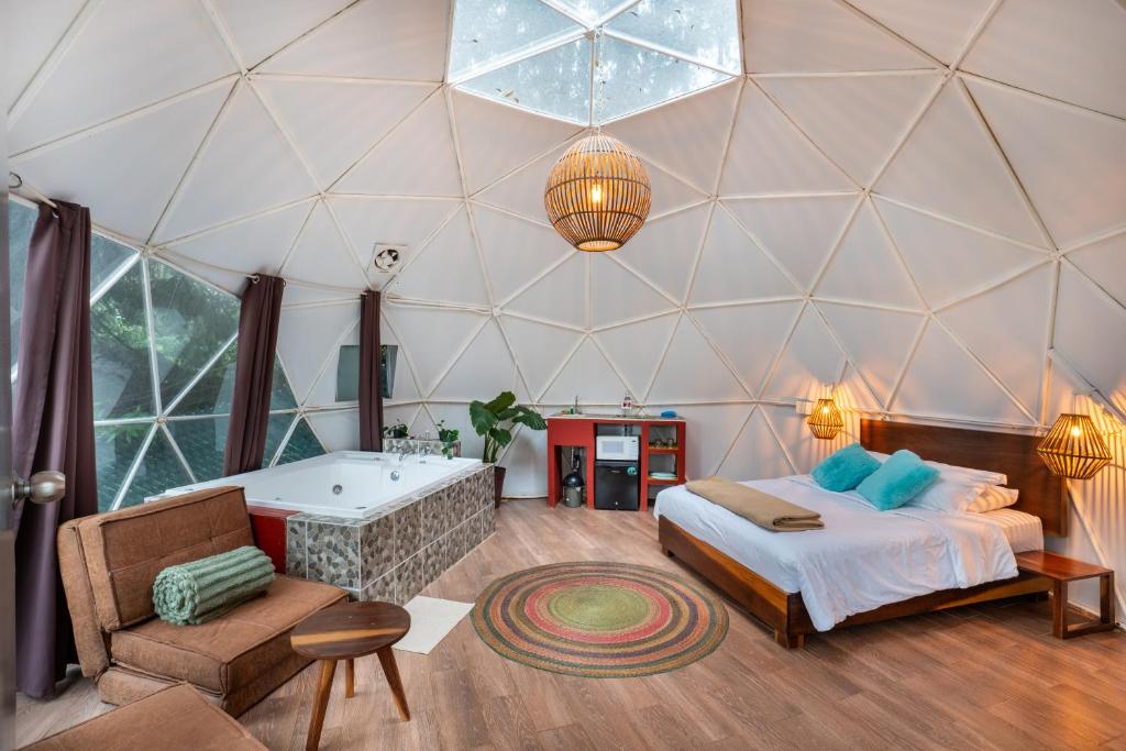 a room with a tub and a bed and a chair at Glamping-Zingo in Santa Ana Jilotzingo