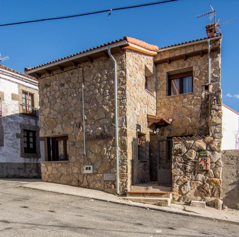 a stone building on the side of a street at El Leñador I in Hoyos del Espino