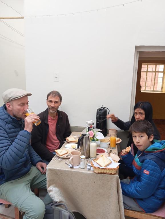 a group of people sitting around a table eating food at Abril Hostel in Mollepata