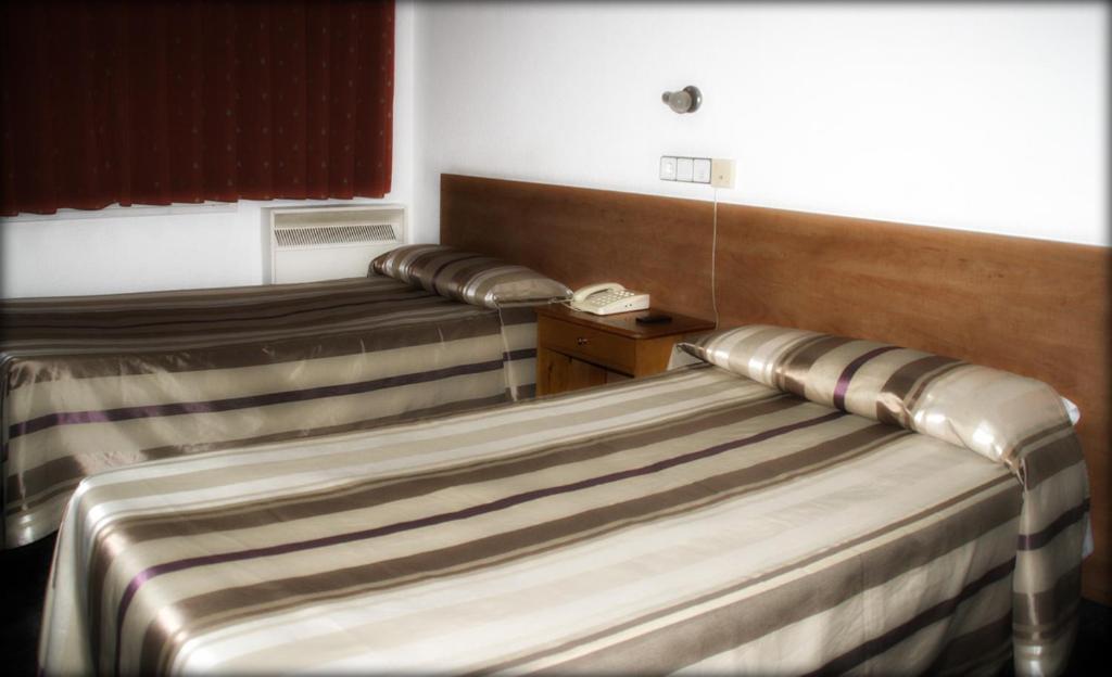 2 camas en una habitación de hotel con teléfono en Hostal Aisa Ochoa, en Zaragoza