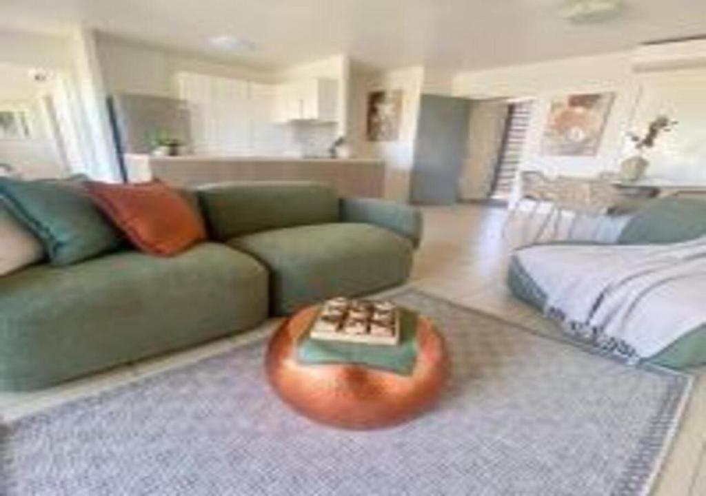 a living room with a green couch and a table at Nature Meets City on Mint in Townsville