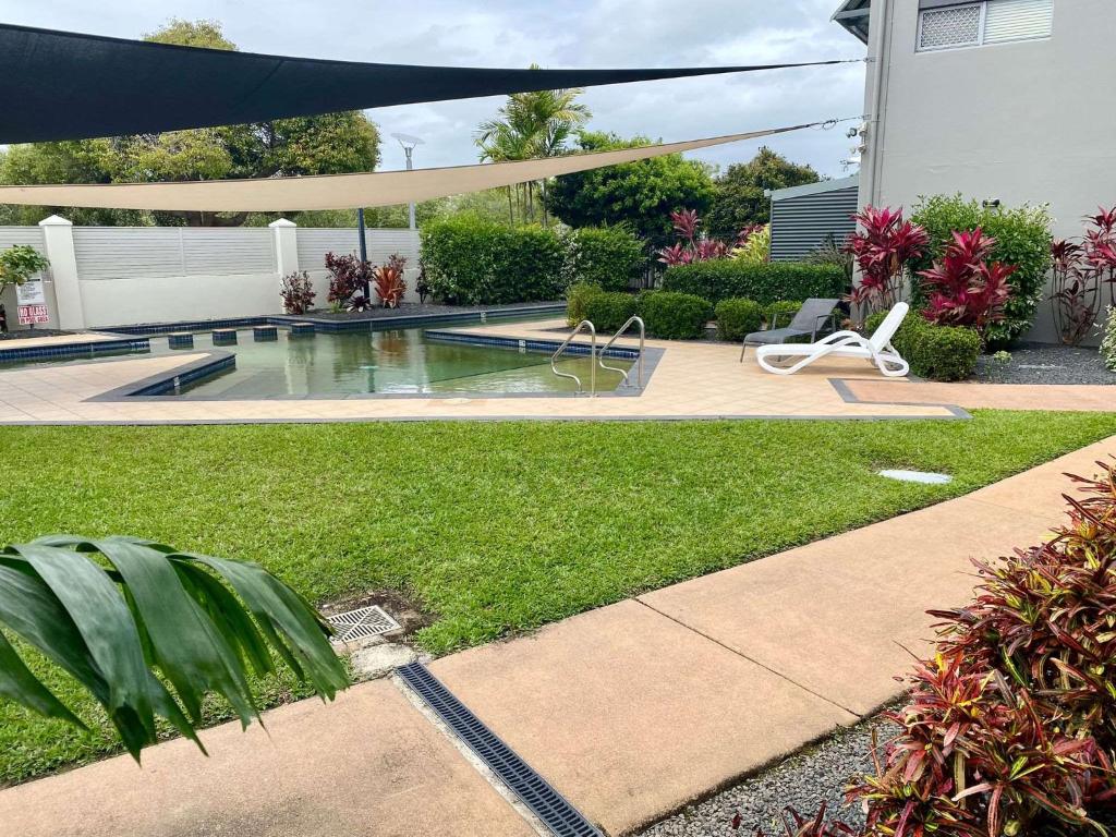 a backyard with a swimming pool and an umbrella at Tranquil 3 Bedroom Retreat in Townsville City in Townsville