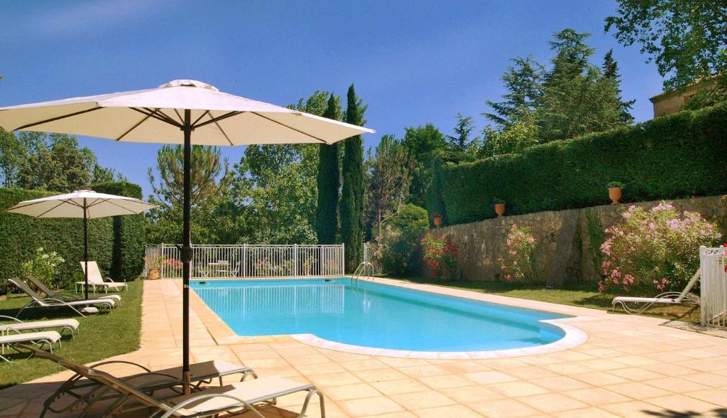 - une piscine avec un parasol et des chaises dans l'établissement Bastide le Luget, à Vénéjan