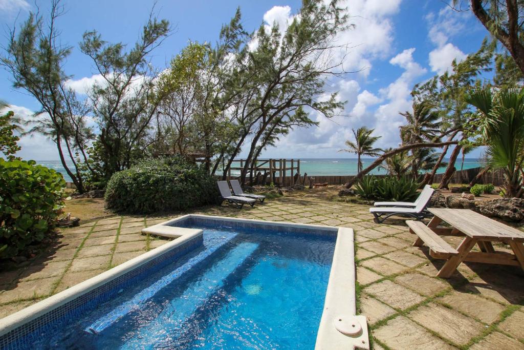 a swimming pool with a picnic table and a bench at Stunning Views Oceanfront Oasis with Private Pool - Inch by Inch in Christ Church