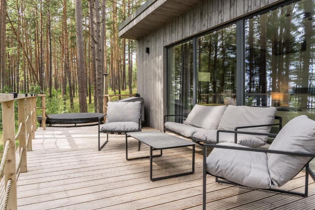a screened in porch with chairs and tables on a deck at Gauja Lakeside in Gauja