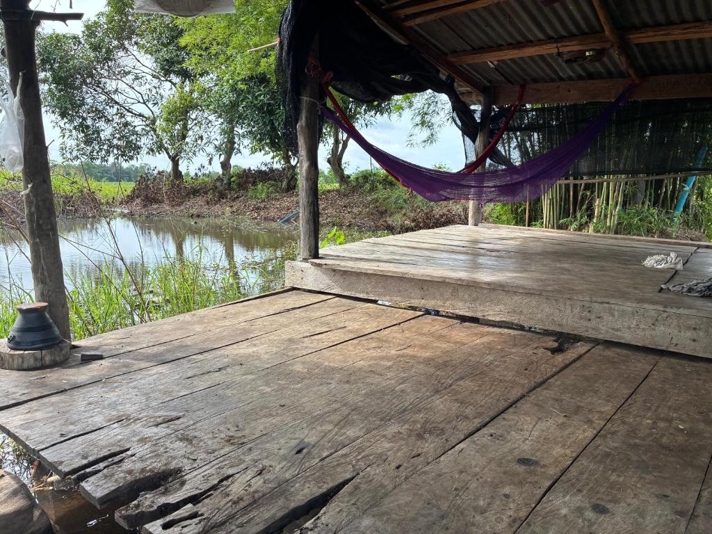 a hammock on a wooden deck next to a river at The Sawmill Lakeside Hut in Ban Nong Sakae
