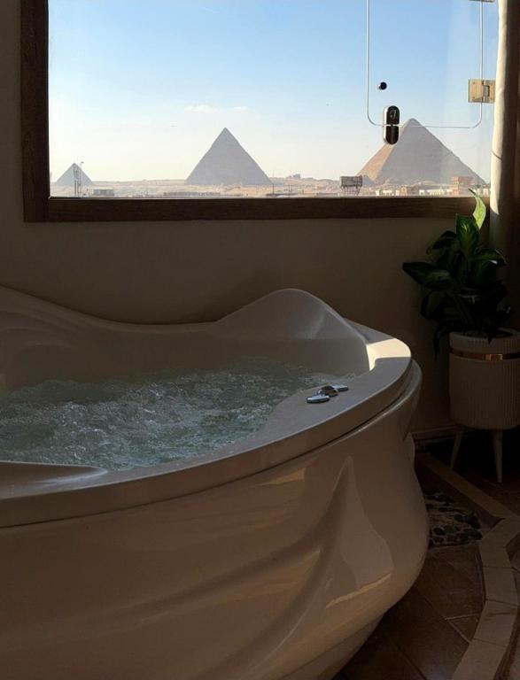 a bath tub with a window with a view of pyramids at Aura Grand pyramids view inn in Giza