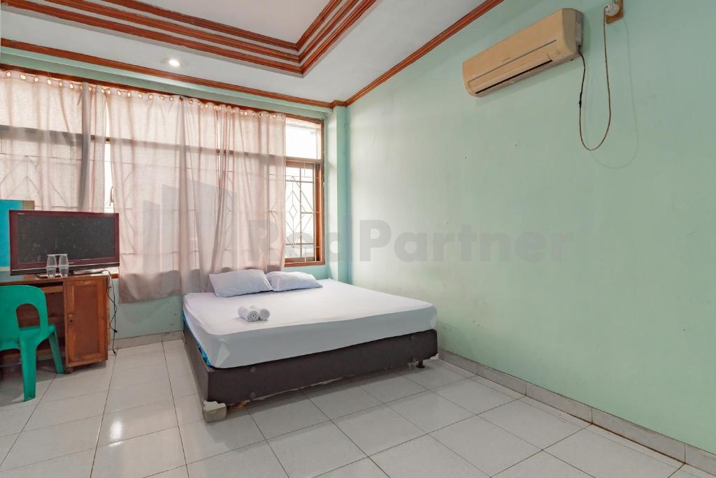 a bedroom with a bed and a desk and a window at Bojongsoang Guesthouse RedPartner in Bandung