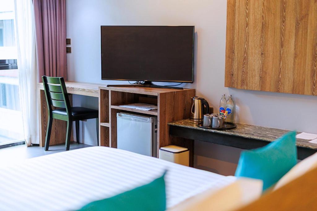 A room corner with a wall-mounted television, compact desk and beverage station.