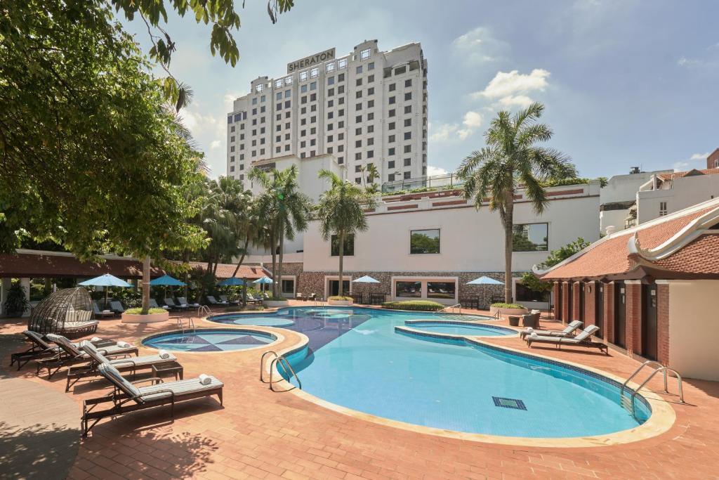 a swimming pool with lounge chairs and a large building at Sheraton Hanoi Hotel in Hanoi