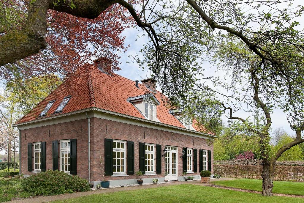 een oud bakstenen huis met een rood dak bij PicaBella - B&B en atelier in Laren