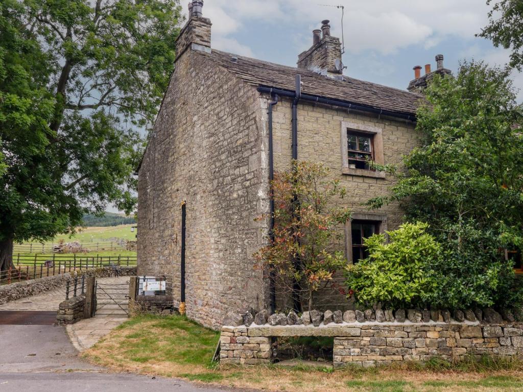 an old stone house with a bench in front of it at Bay Horse Cottage in Skipton