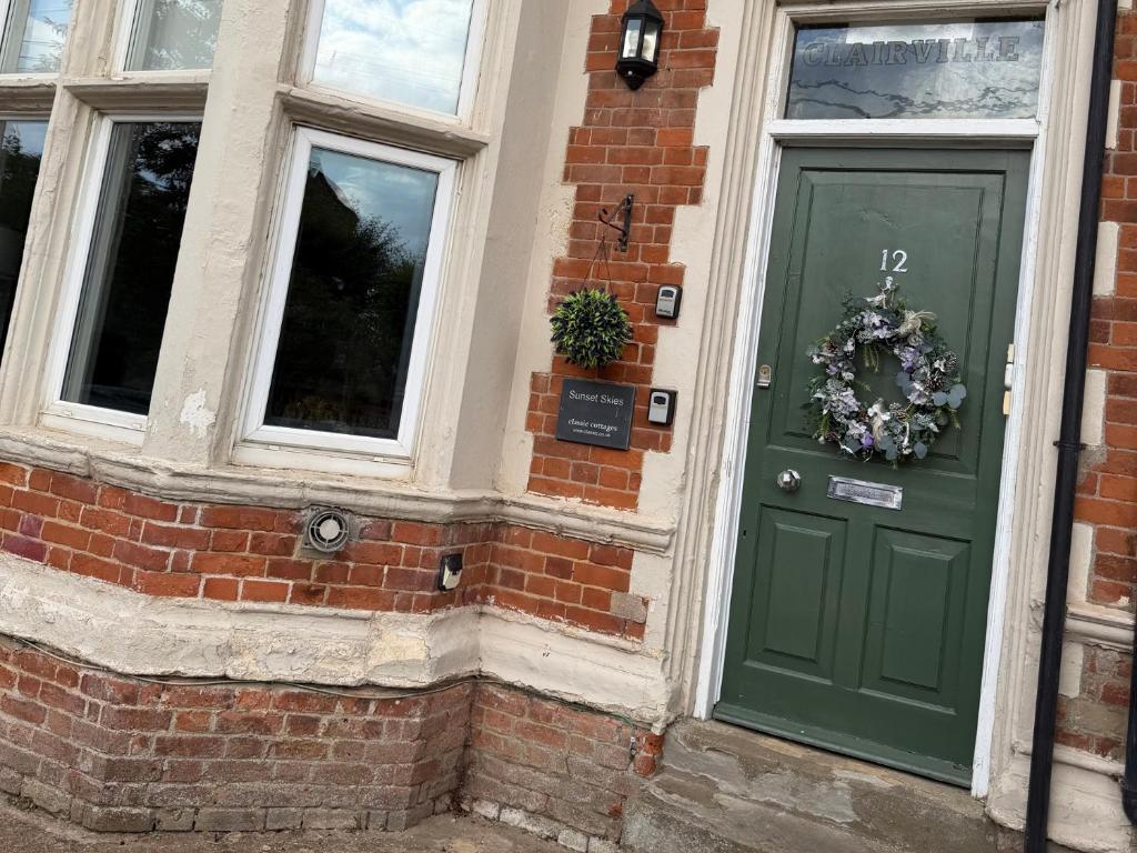 a green door on a brick building with windows at Northgate Ground Floor Flat in Hunstanton
