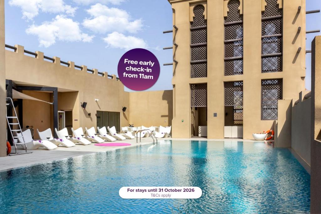 a pool in the middle of a building with chairs at Premier Inn Dubai Al Jaddaf - An Emirates Group Company in Dubai