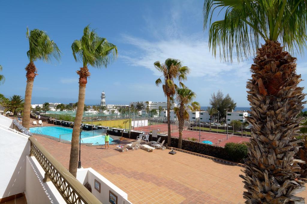 un balcón con palmeras y una piscina en Playa Grande Puerto del Carmen Share Pool By PVL, en Puerto del Carmen