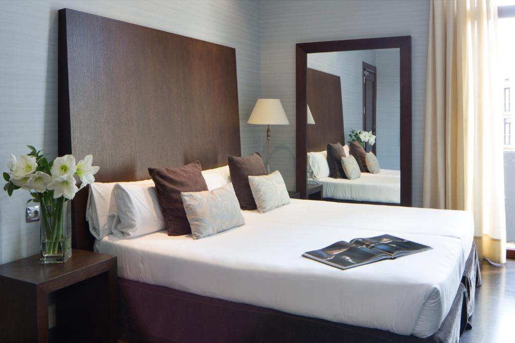 ein Hotelzimmer mit einem großen weißen Bett und einem Spiegel in der Unterkunft Hotel Ramblas Internacional in Barcelona