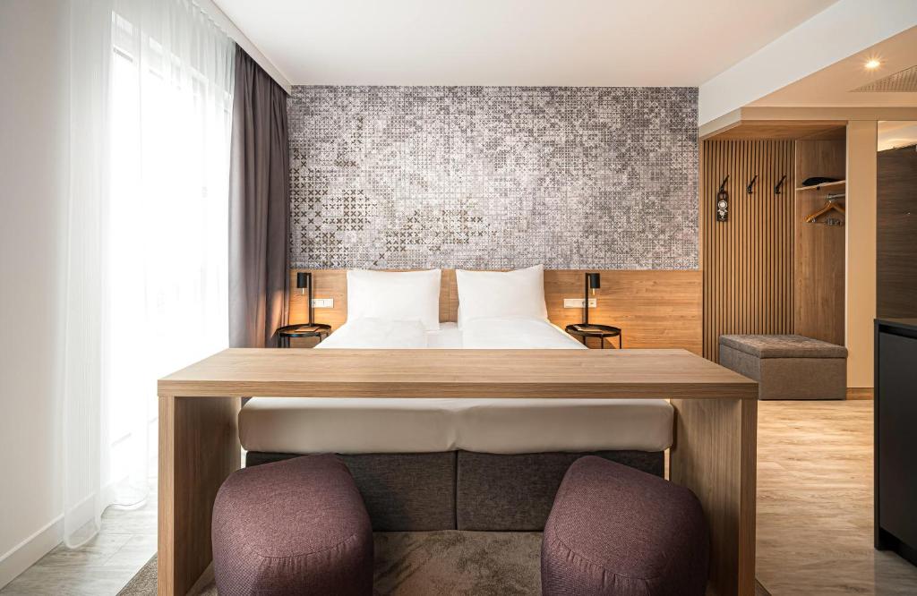 a bedroom with a bed and two chairs at elaya hotel augsburg, Trademark by Wyndham in Augsburg