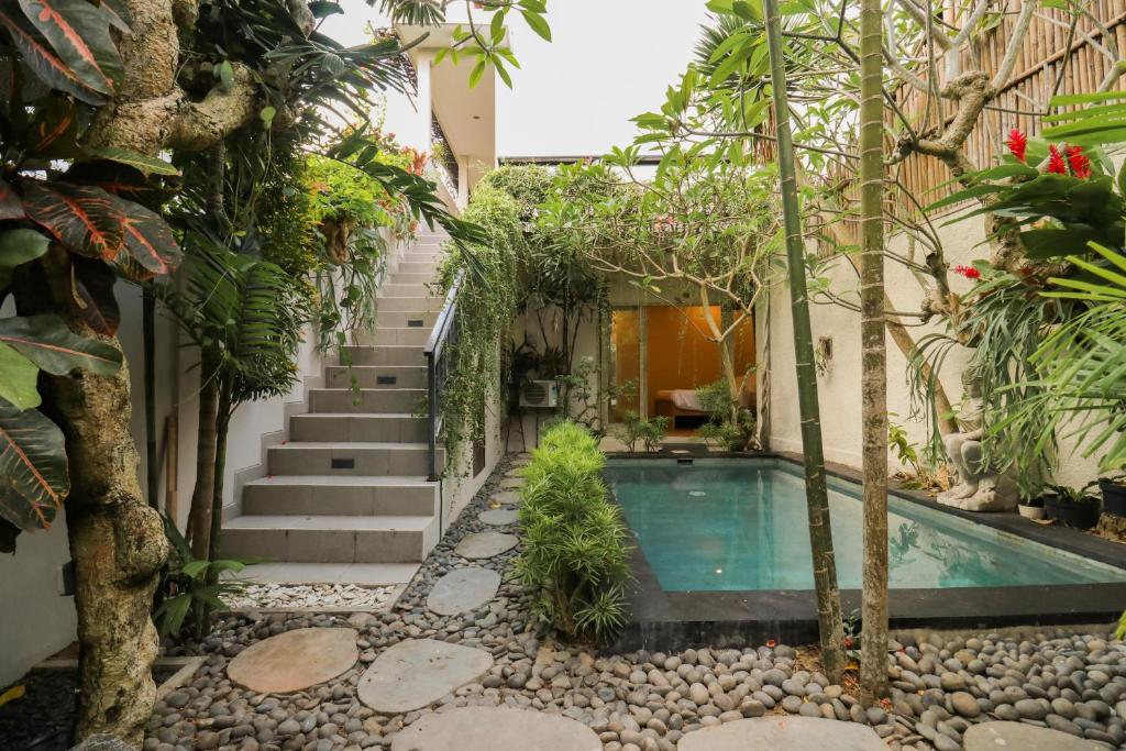 a courtyard with a swimming pool and trees at Neduh House Pererenan in Pererenan