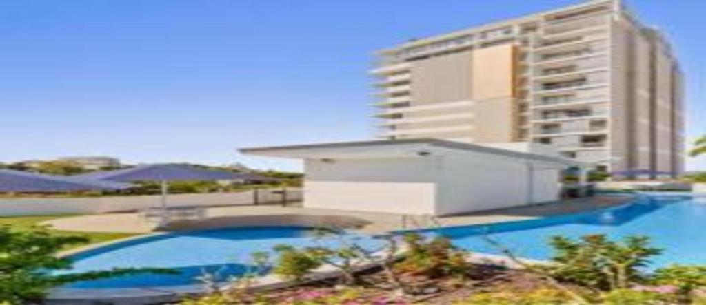 a swimming pool with a tall building in the background at Dalgety 104 in Townsville