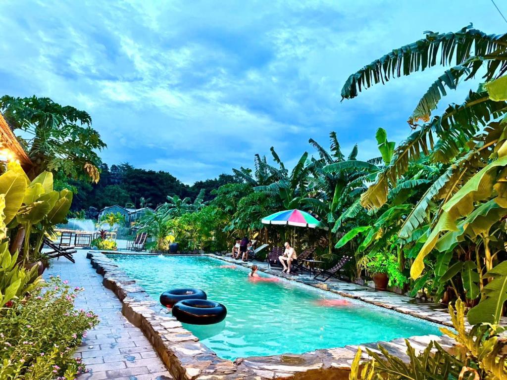 a pool at a resort with people in the water at Rocky Mountain Ecolodge in Xuân Sơn