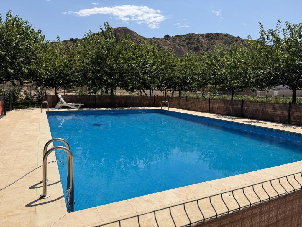 a swimming pool with blue water in a yard at Granja escuela con bungalows Familias y grupos Parking privado gratuito in San Martín de la Vega