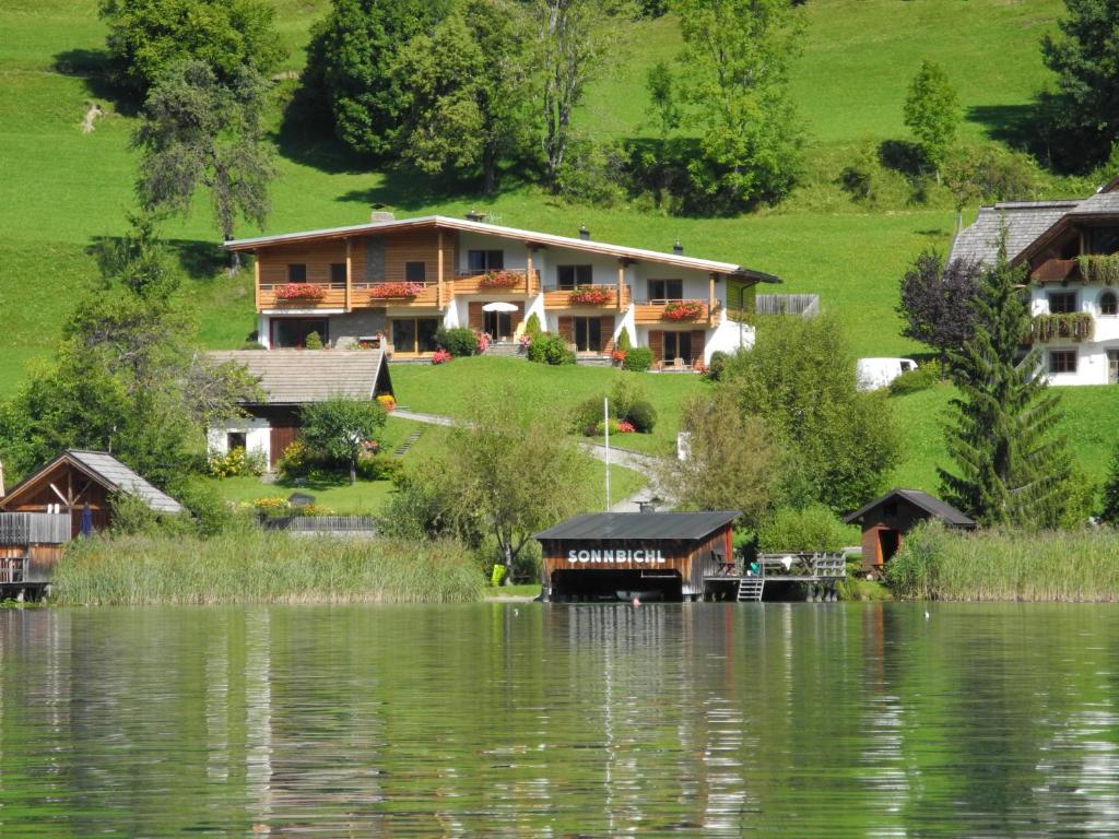 a large house on the side of a lake at Haus Sonnbichl in Weissensee