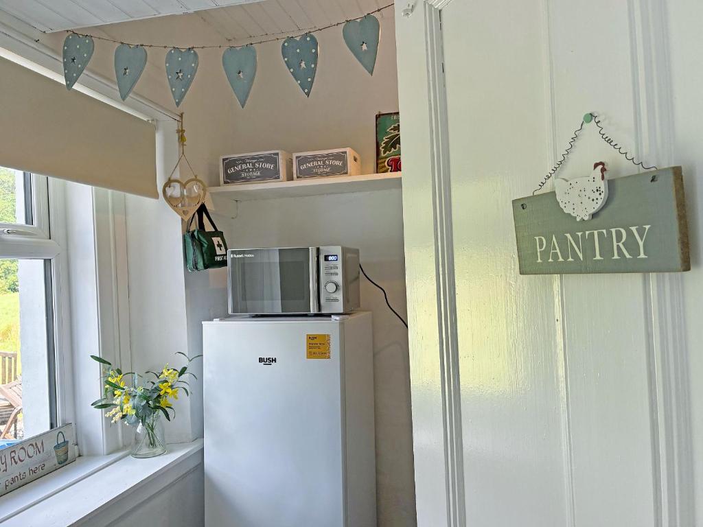 a white refrigerator in a room with a pharmacy sign at Kirnan Cottage in Kilmichael Glassary