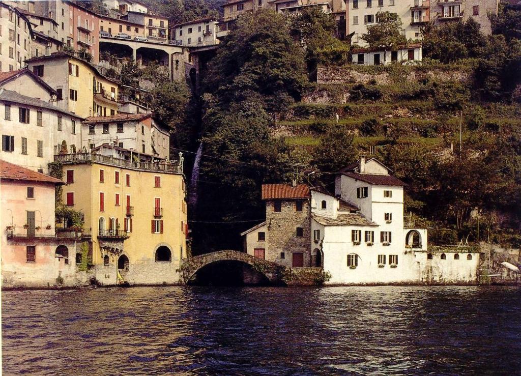 a group of buildings on a hill next to the water at La Ruota del Mulino in Nesso