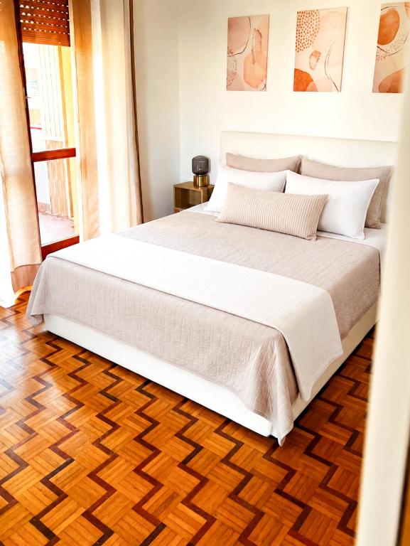 a large white bed in a bedroom with a wooden floor at Casa Lupoli in Caserta