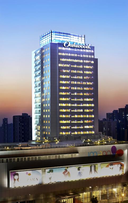 a tall building with a sign on top of it at Oakwood Residence Shanghai in Shanghai