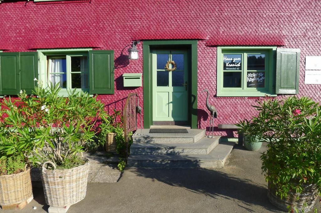 a pink building with a green door and some plants at Haus zum Kranich, traditionelles, charmantes, ehemaliges Bauerngasthaus in Möggers