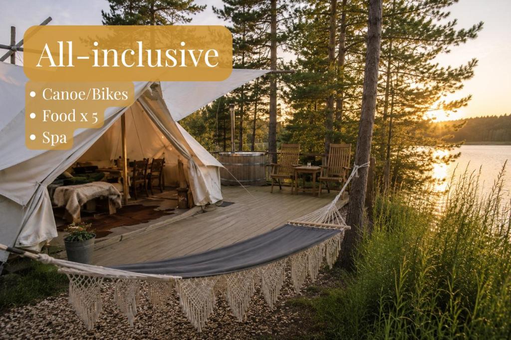 a tent with a hammock next to a lake at Vristulvens Glamping in Mariestad
