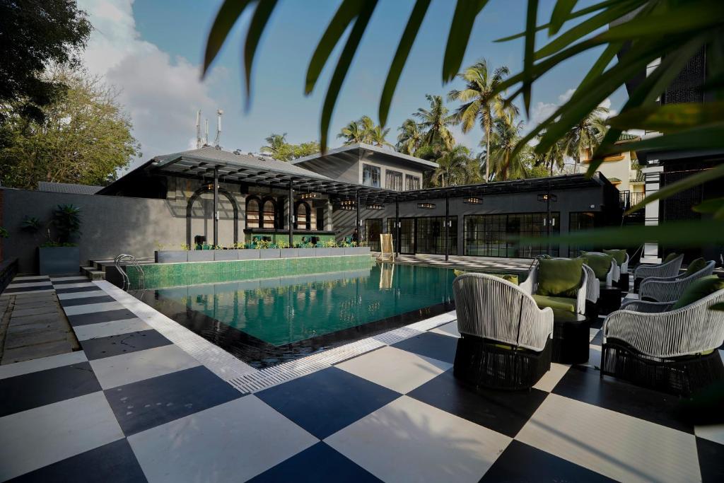 a swimming pool with chairs next to a building at King's Mansion in Candolim